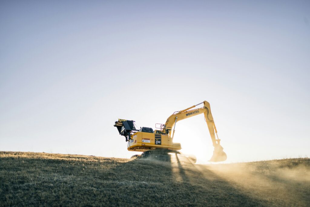 Yellow excavator working at a construction site at sunset