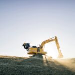 Yellow excavator working at a construction site at sunset