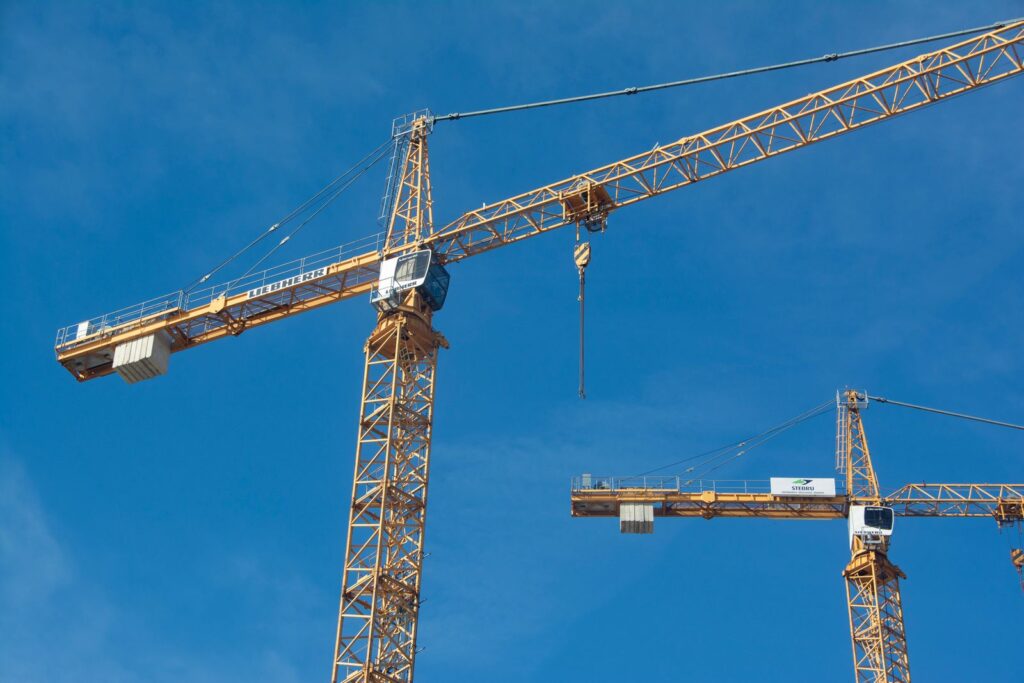 Yellow tower cranes against a clear blue sky
