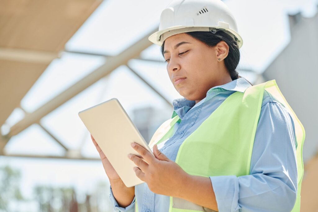 Engineer in a hard hat using a digital tablet at an industrial site